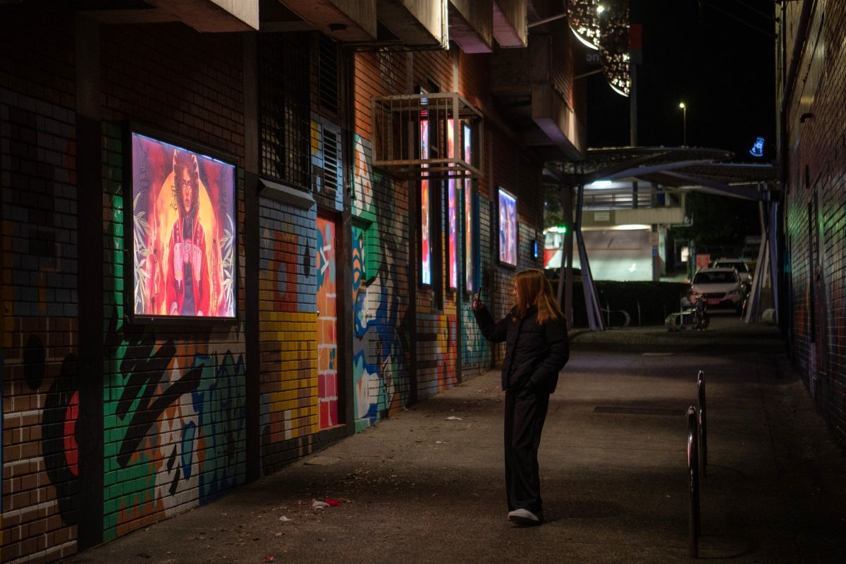 Lightboxes on the wall down an alleyway covered in graffiti