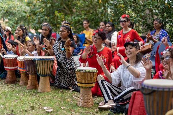 Women and children in national dress participating in a drumming workshop
