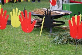 Cardboard hands painted red, yellow and black on grass for National Sorry Day