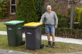 Male resident standing on the street with two waste bins
