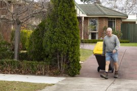 man walking wheelie bin to the kerb