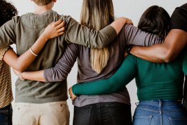 Backs of five people linking arms