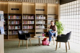 Image of adult female sitting in Bayswater Library reading