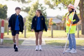 Two children and a school crossing supervisor crossing a road