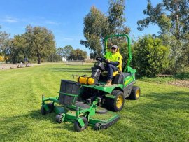 Parks maintenance staff member operating a grass mower