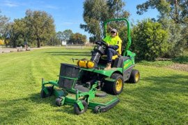 Parks maintenance staff member operating a grass mower