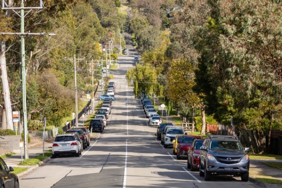 Tree lined street with cars parked on either side of the road