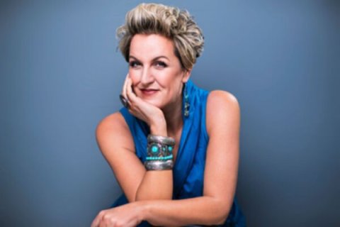 A woman in blue with her hand under her chin