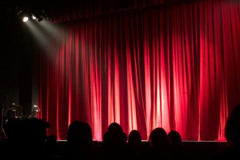 Photo of a theatre stage with red curtains closed