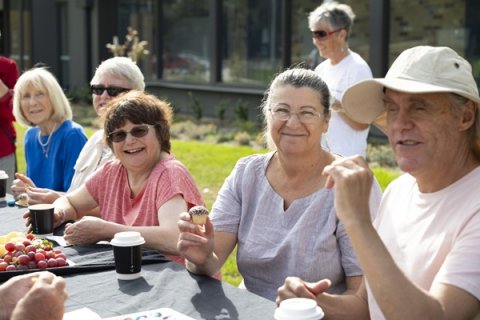 Group of people together around a table having morning tea.