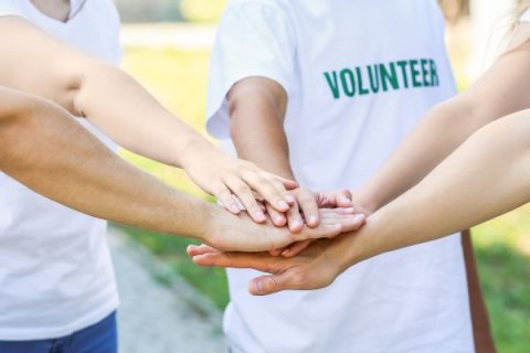 Group of volunteers putting hands together outdoors