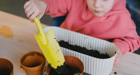 A child with a pot of soil